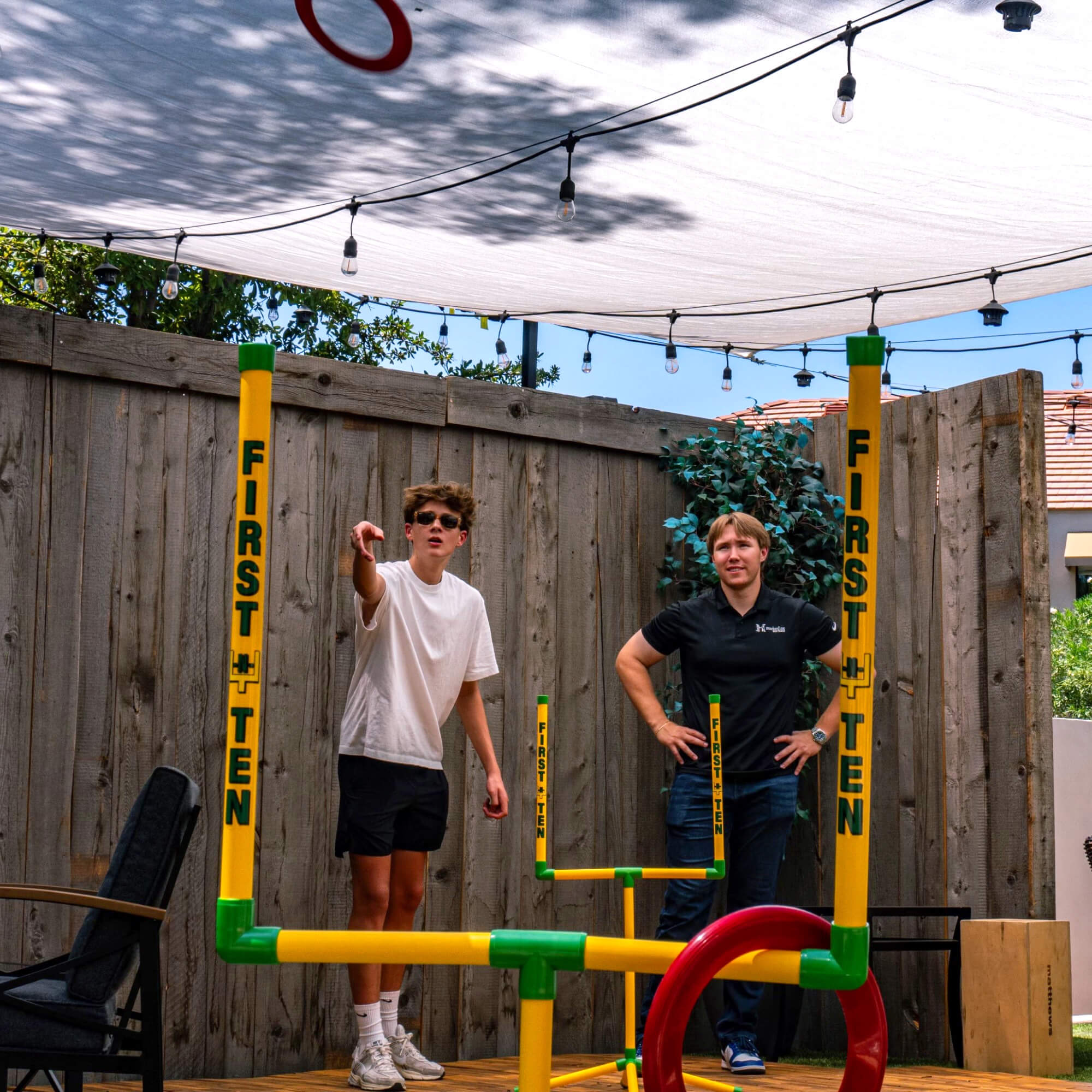 Two friends standing behind a First-N-Ten post, engaged in the game