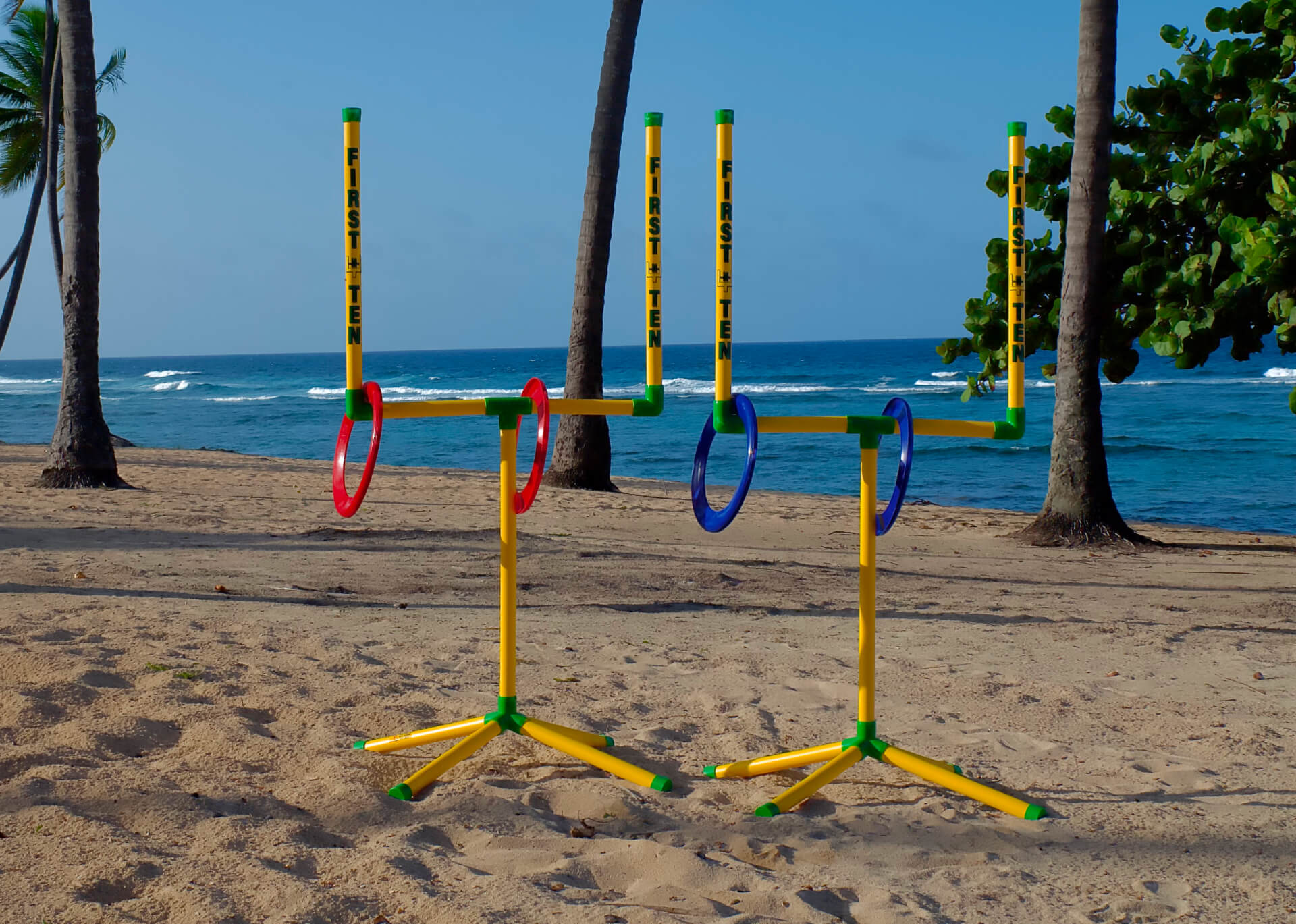 Two First-N-Ten goalposts on the beach against a tropical blue ocean