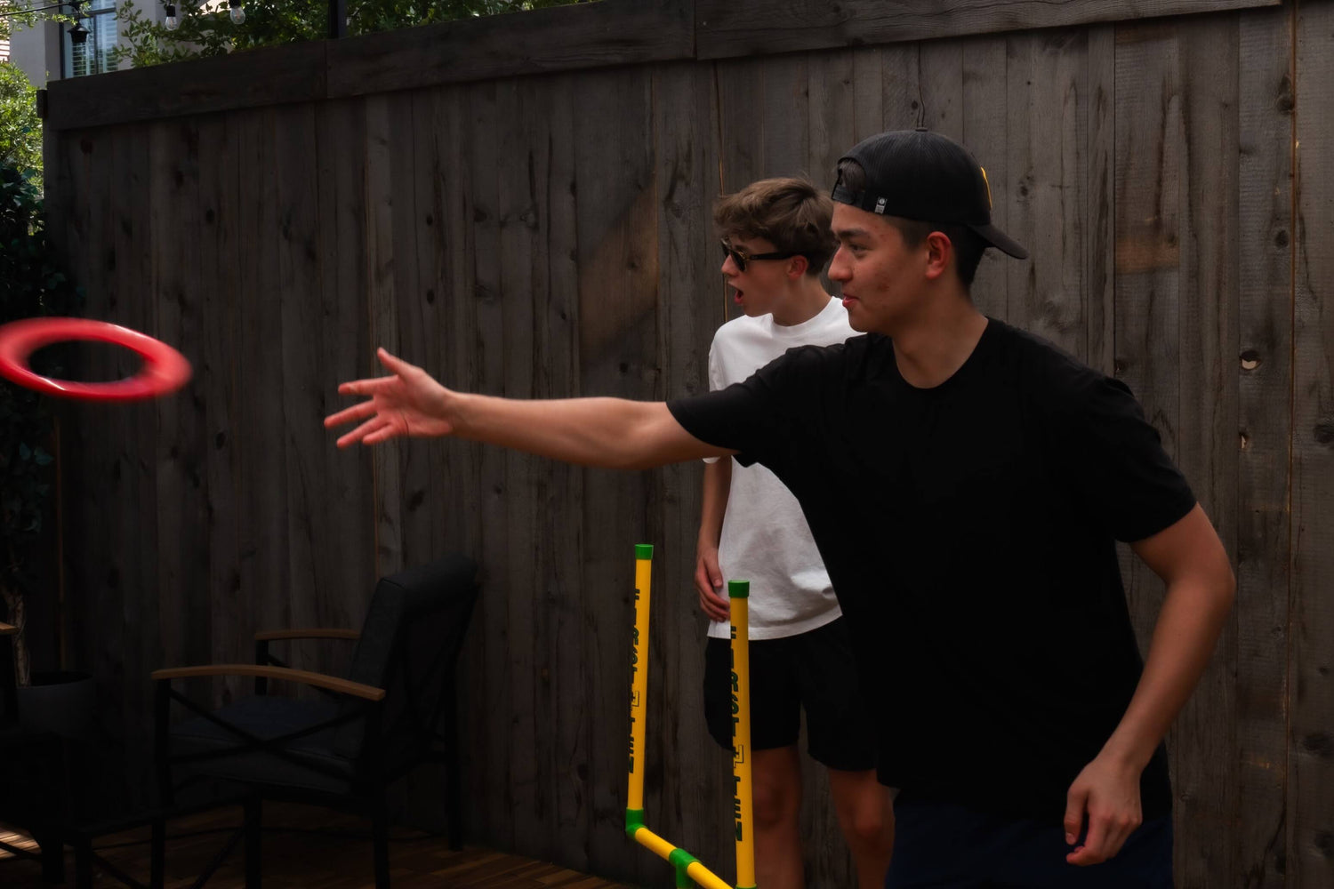 Spencer throwing a red First-N-Ten ring in a backyard